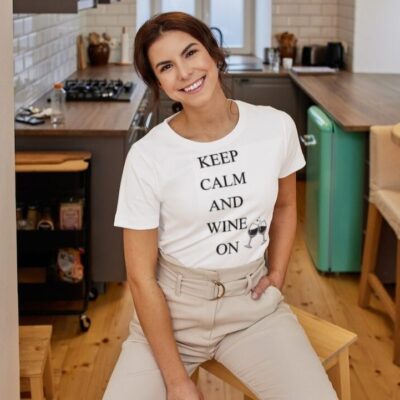 A girl wearing a white T-shirt with writing that says "Keep Calm and Wine On" vertically and two glasses of wine next to "wine and on "