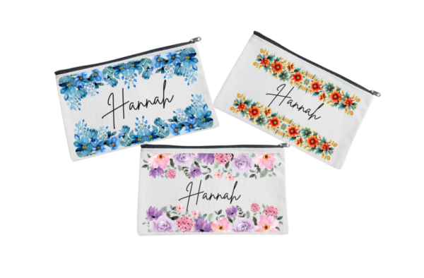 Three personalized pouches with A name written on them, adorned with different floral designs.