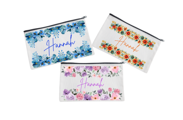 Three personalized pouches with A name written on them, adorned with different floral designs.