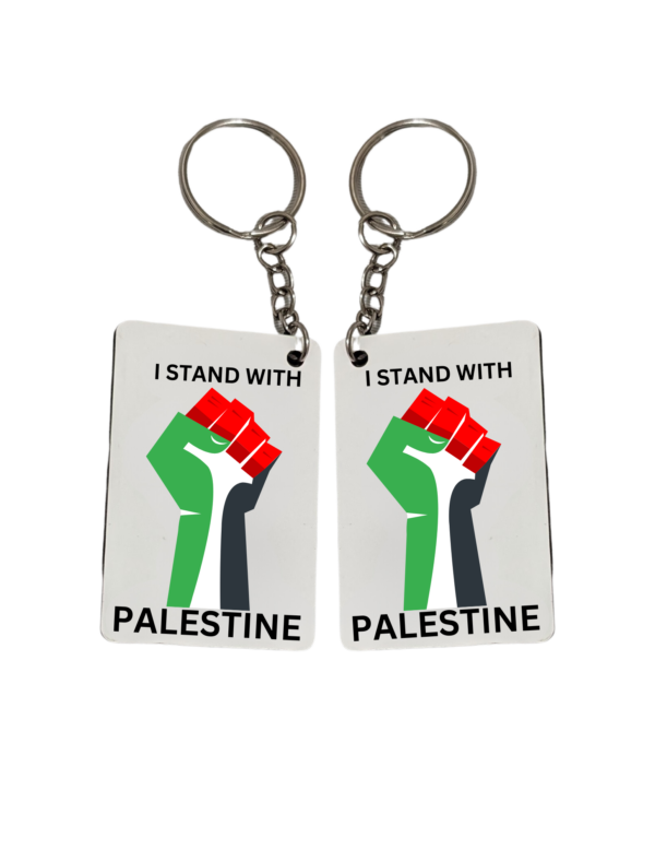 Two square keychains with a graphic of a raised fist in front of the Palestinian flag and text that reads ‘I STAND WITH PALESTINE.